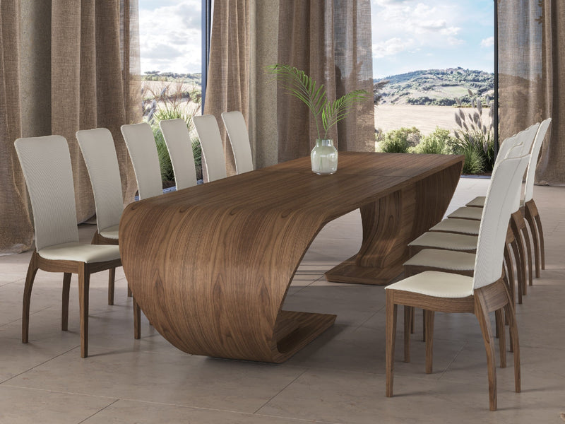 A wooden table with a unique curved design and eight white chairs