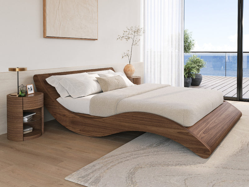 Modern wooden bed with white bedding and pillows in a serene room with a large window overlooking the ocean.